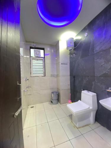 a bathroom with a toilet and a sink and a blue light at Revanta Home Stay in Anandpur Sāhib