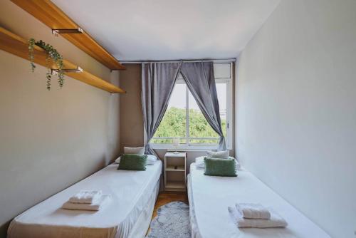 two beds in a room with a window at 3 bedroom Huge apartament near the beach in Sant Adria de Besos