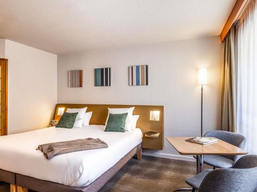 a hotel room with a bed and a table and chairs at Novotel Lille Centre Gares in Lille