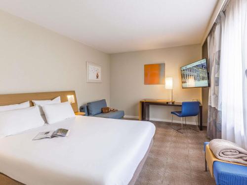 a hotel room with a large white bed and a desk at Novotel Lille Centre Gares in Lille