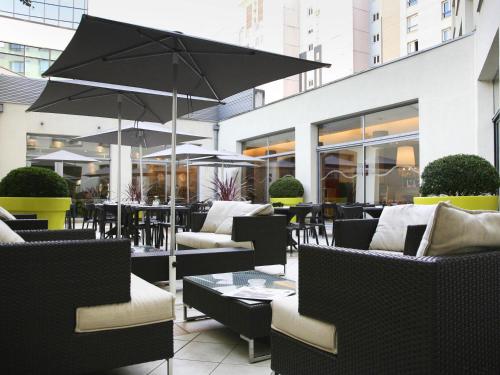 a patio with chairs and tables and an umbrella at Novotel Lille Centre Gares in Lille