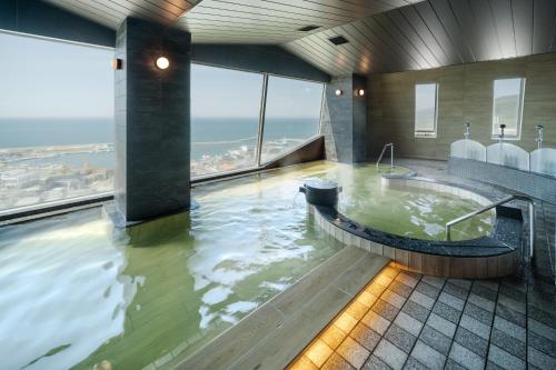 a hot tub in a bathroom with a view at KAMENOI HOTEL Awajishima in Awaji
