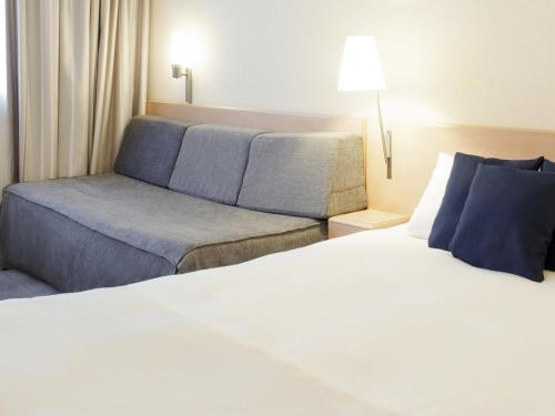 a hotel room with a bed and a couch at Novotel Ieper Centrum in Ypres