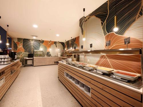 a restaurant with a counter with food on it at Novotel Ieper Centrum in Ypres