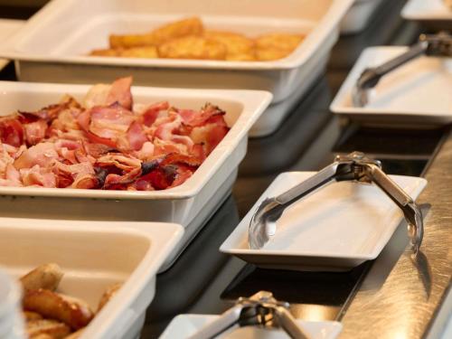a buffet with several trays of food on a table at Novotel Ieper Centrum in Ypres
