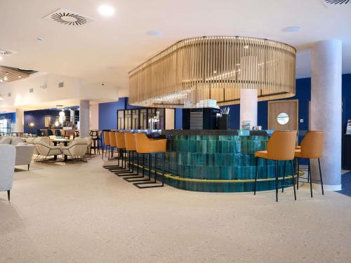 a lobby with a bar with chairs and tables at Novotel Ieper Centrum in Ypres