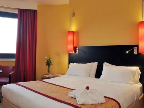 a hotel room with a bed with a towel on it at Hotel Mercure Alger Aéroport in Dar el Beïda