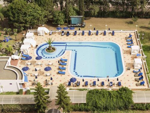 an overhead view of a large swimming pool with chairs and people at Hotel Mercure Alger Aéroport in Dar el Beïda