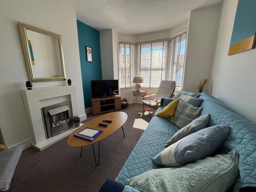 a living room with a blue couch and a fireplace at 11B Beachside in Eastbourne
