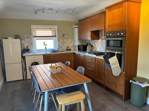 a kitchen with a wooden table and a table and a refrigerator at 11B Beachside in Eastbourne