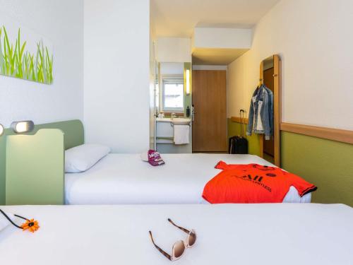 a hotel room with two beds with glasses on them at ibis budget Zurich City West in Zürich