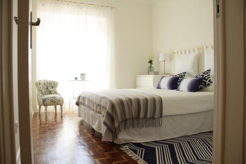 a bedroom with a bed with blue pillows and a chair at Apartment House in Costa da Caparica