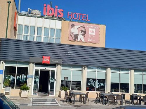 a store with tables and chairs in front of a building at Ibis Hotel Alicante in Alicante
