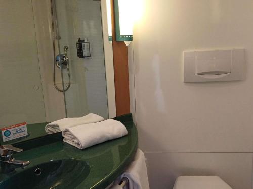 a bathroom with a sink and a toilet and a mirror at Ibis Hotel Alicante in Alicante