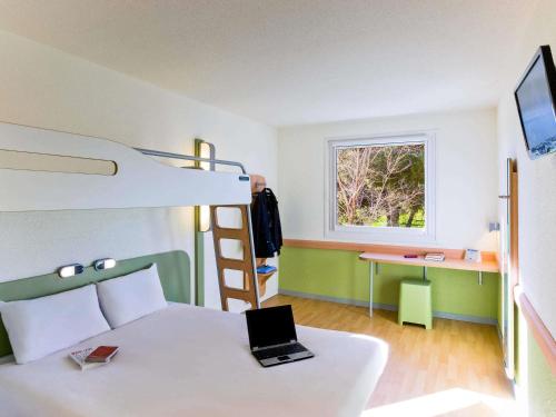a bedroom with a bed with a laptop on it at Ibis Budget Madrid Alcalá de Henares La Dehesa in Alcalá de Henares