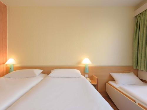 two beds in a room with two lamps at Ibis Hotel Alicante in Alicante