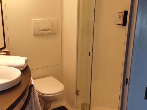 a small bathroom with a toilet and a shower at Ibis Hotel Alicante in Alicante