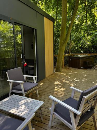 two chairs and a table on a wooden deck at Lodge en pleine nature in Gouvieux
