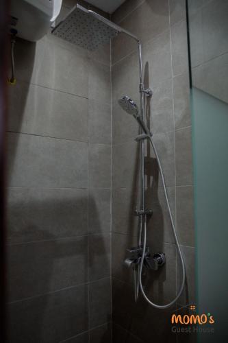 a shower with a glass door in a bathroom at Momo's Guest House in Kumasi