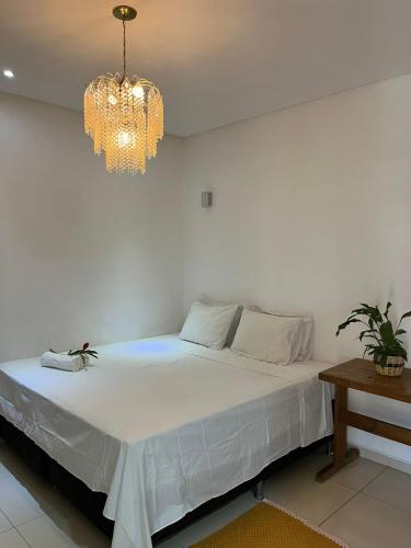 a bedroom with a white bed with a chandelier at Casa Lalivi Trancoso in Porto Seguro
