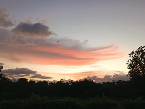 a sunset with clouds in the sky over trees at Apartment-Pura Vida-wi-fi-6 people, AC- parking-river-garden in Fortuna