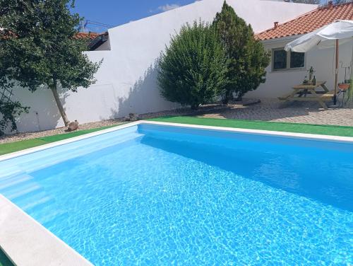 a blue swimming pool in front of a house at Quintal do Olival- Um refúgio na Natureza in Lousã