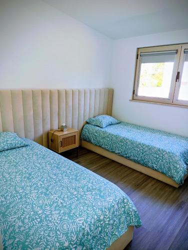 a bedroom with two beds and a window at Quintal do Olival- Um refúgio na Natureza in Lousã