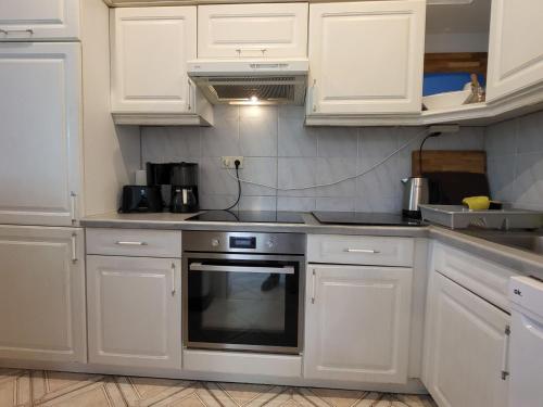 a kitchen with white cabinets and a stove top oven at Apartment Terrassenwohnung am See by Interhome in Neuglobsow