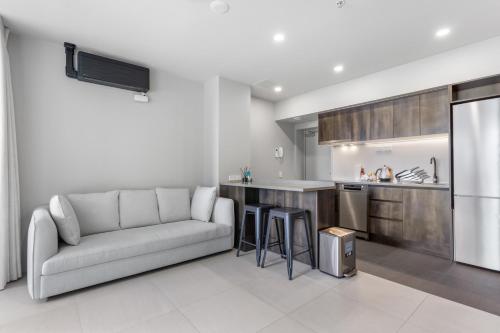 a living room with a couch and a kitchen at QV Stays Modern City Retreat in Auckland