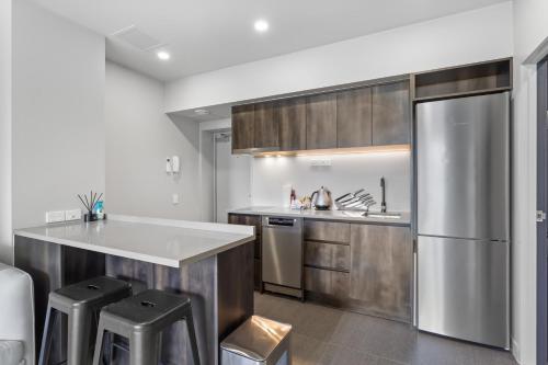a kitchen with a stainless steel refrigerator and stools at QV Stays Modern City Retreat in Auckland