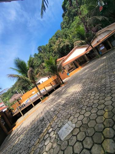 a cobblestone street with palm trees and a building at Chalé Residencial Bosque da Cocanha in Caraguatatuba
