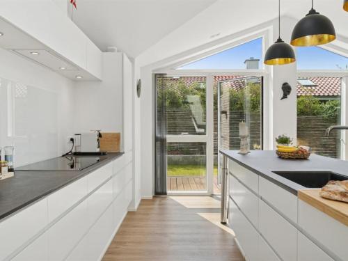 a kitchen with white cabinets and a large window at Holiday Home Troels - 945m from the sea by Interhome in Hornbæk