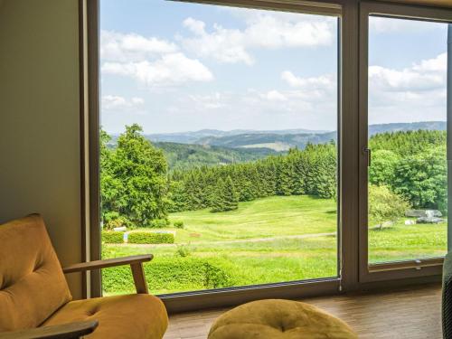 a living room with a large window looking out at a green field at Holiday Home de luxe H751 mit Panoramasauna by Interhome in Masserberg