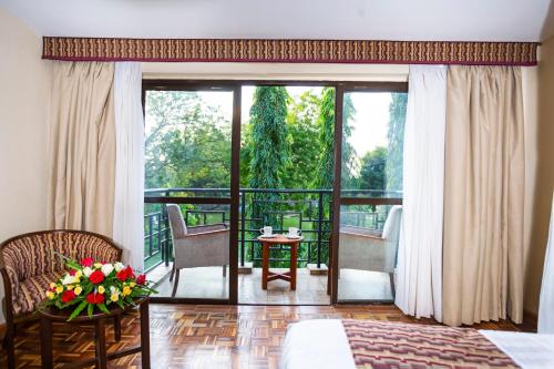 a room with a bed and a balcony with a view at Lake Bogoria Spa Resort in Marigat