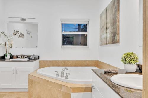 a white bathroom with a tub and a sink at Casa Stella Tropical Pool Beach 8 min in Hollywood