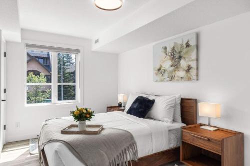 a white bedroom with a bed and a window at Newly Built 2BR and 2BA MtnView Retreat in DT Canmore in Canmore