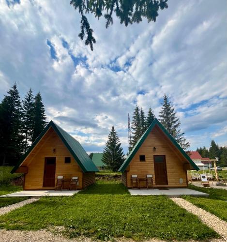 a couple of buildings with chairs in the grass at Cottage Sanja in Žabljak
