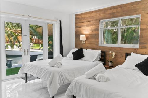 two beds in a room with two windows at Casa Agape Waterfront HotTub 15 min to Beach in Hollywood