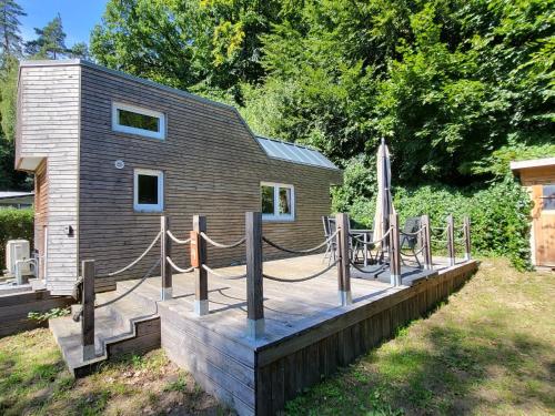 a cabin with a deck with a table and an umbrella at Holiday Home -2 by Interhome in Stuer