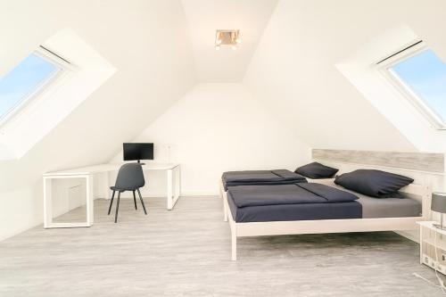 a white bedroom with a bed and a desk at Haus Auszeit in Cremlingen