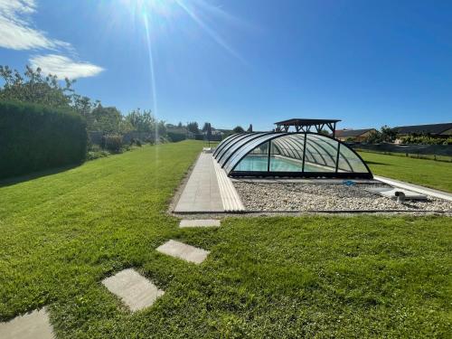 a glass house in a grassy field with the sun at Margaret Apartment in Balatonkeresztúr