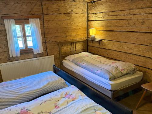 two beds in a room with wooden walls at Chalet Schipplbadstube by Interhome in Annaberg im Lammertal