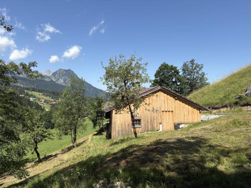 a barn on a hill with mountains in the background at Chalet Schipplbadstube by Interhome in Annaberg im Lammertal