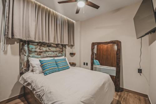 a bedroom with a bed with a ceiling fan and a mirror at Breezy elegance Sayulita style in Sayulita