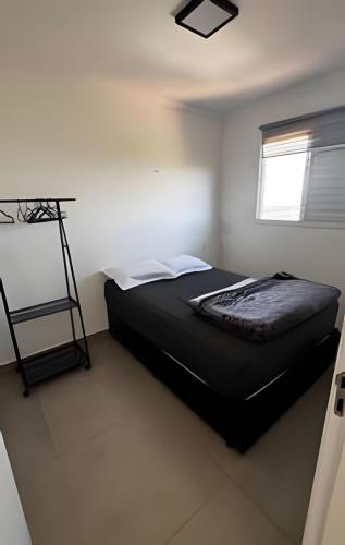 a bedroom with a black bed in a white room at Apartamento inteiro com vaga, varanda e piscina in Cotia