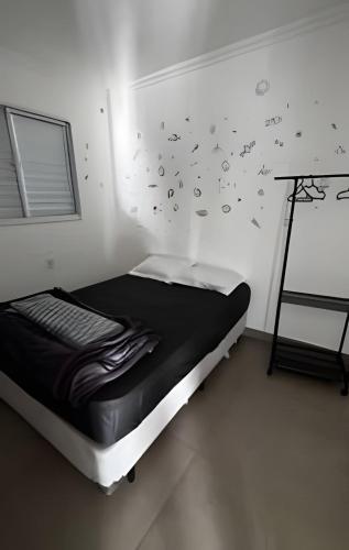 a bedroom with a bed with black sheets and butterflies on the wall at Apartamento inteiro com vaga, varanda e piscina in Cotia