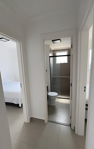a white room with a bed and a toilet at Apartamento inteiro com vaga, varanda e piscina in Cotia