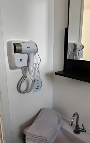 a hair dryer hanging on a wall next to a mirror at Apartamento inteiro com vaga, varanda e piscina in Cotia