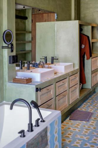 a bathroom with three sinks and a large mirror at Sumba Lodge in Manuel Antonio
