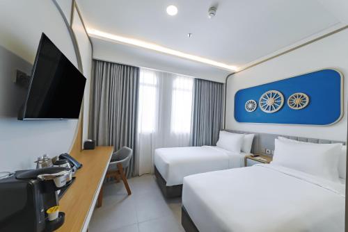 a hotel room with two beds and a tv at Truntum Cihampelas in Bandung